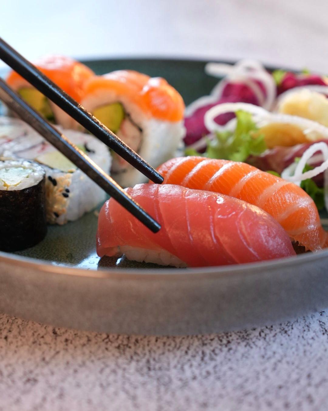 Nigiri mit Lachs und Thunfisch bei Mami Viet Leipzig, aufgenommen mit Stäbchen von einem Teller mit Maki und Inside-out-Rollen